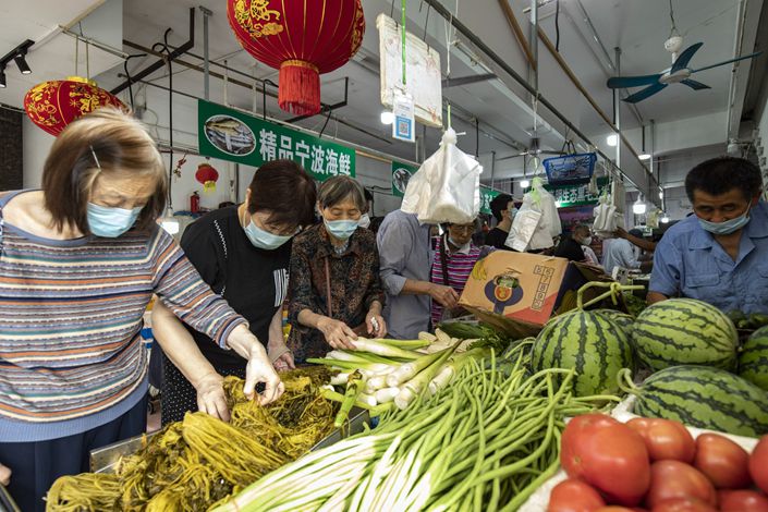 Customers purchase vegetables at a market in Shanghai on June 6. Photo: Bloomberg