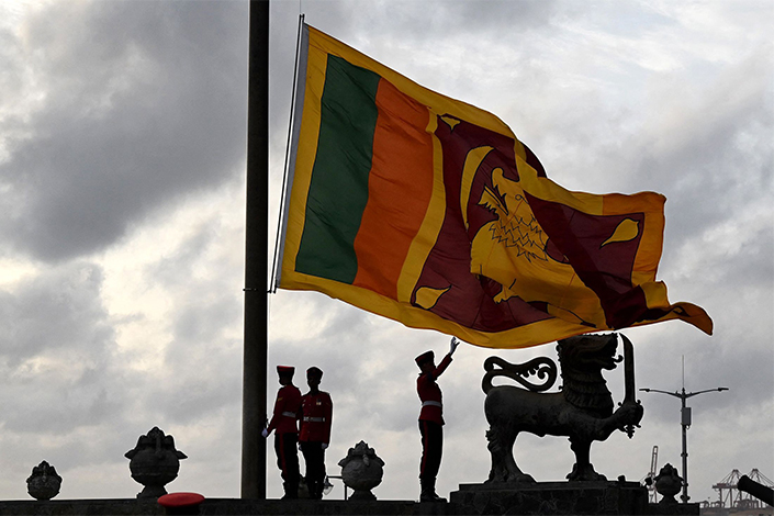 Military personnel in ceremonial uniform lower the Sri Lanka national flag at Galle Face Green in Colombo on July 23. Photo: Bloomberg