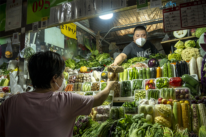 A vegetables vendor serves a customer at a food market in Beijing, China, on Thursday, Aug. 4, 2022. Photo: Bloomberg