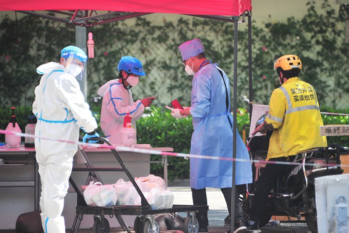 A takeout driver has his digital health code checked by epidemic control workers at the entrance to a community in Shanghai's Yangpu district on May 6. Photo: The Paper