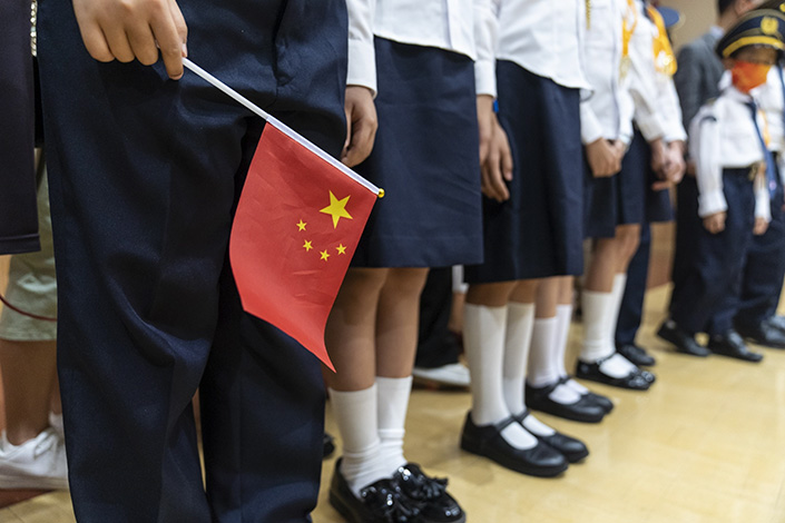 A student holds the national flag during a ceremony at Fukien Secondary School marking National Day in Hong Kong on Oct. 1, 2021. Photo: Bloomberg