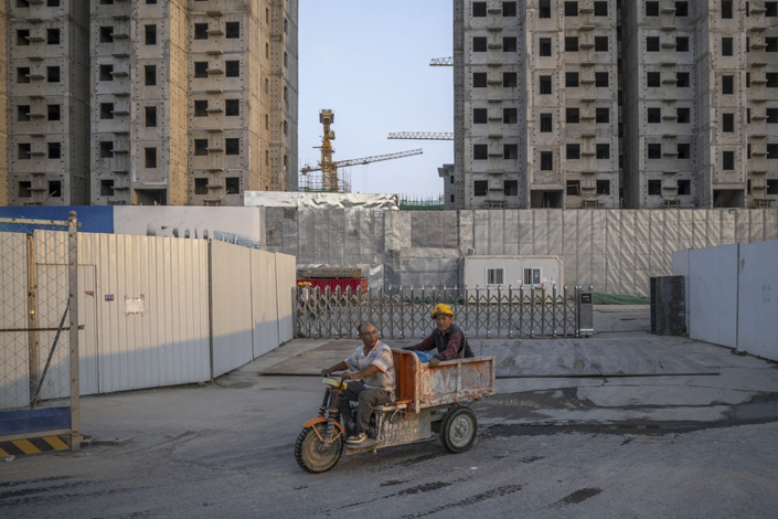 Workers ride a tricycle as they leave the China Evergrande Group Royal Peak residential development in Beijing on July 29. Photo: Bloomberg