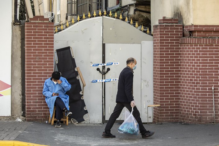 A worker in protective gear guards an entrance to a neighborhood placed under lockdown due to Covid-19 in Shanghai on Monday. Photo: Bloomberg