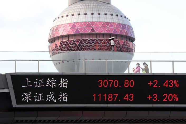 People cross a pedestrian bridge which displays the numbers for the local stock indexes on Nov. 4 in Shanghai.