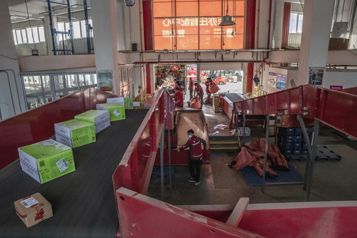 Workers unload parcels onto a conveyor belt at a JD.com sorting center in Beijing in October 2021. Photo: Bloomberg