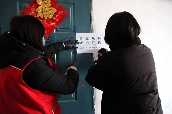 Community workers put up home isolation seals on the door of a resident who returned to Beijing from a high-risk area for getting infected with Covid-19. Photo: VCG