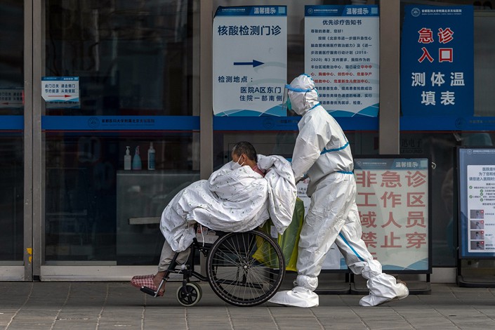 A medical worker in protective gear pushes a patient in a wheelchair at a hospital in Beijing on Wednesday. Photo: VCG