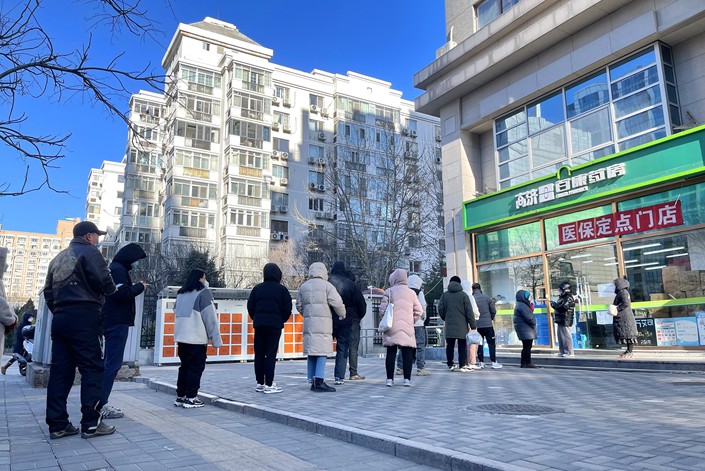 Customers line up in front of a pharmacy to buy medicine on Friday in Beijing. Photo: VCG
