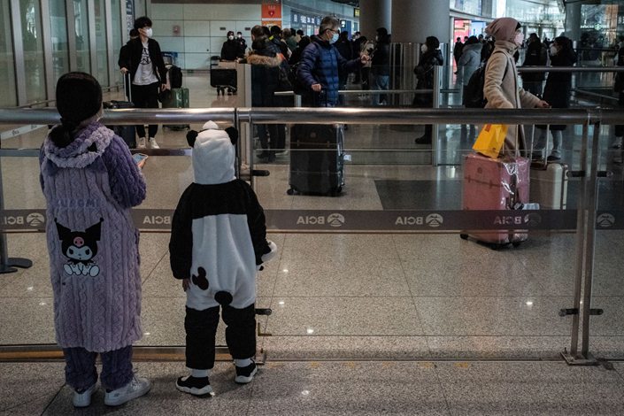 Two children wait for a relative in the arrival hall for international flights at Beijing Capital Airport on Jan. 8. Photo: Bloomberg