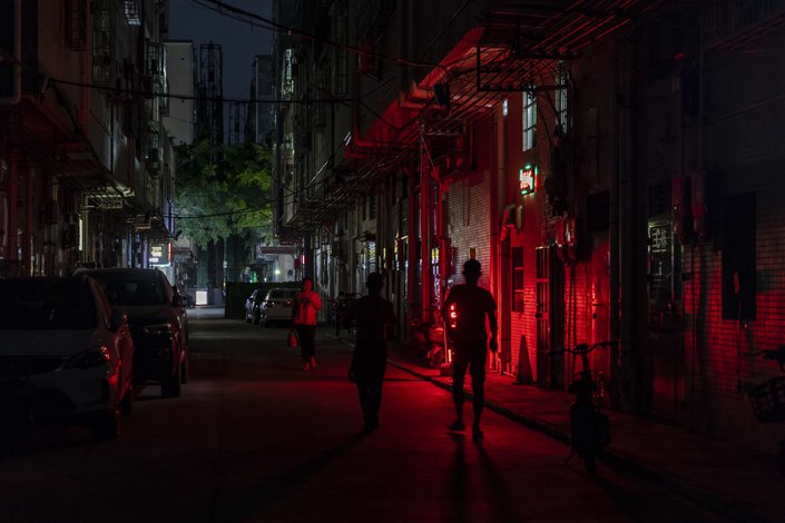 Pedestrians pass a sign for a restaurant illuminated at night on Oct. 13 in Dongguan, South China’s Guangdong Province. Photo: Bloomberg