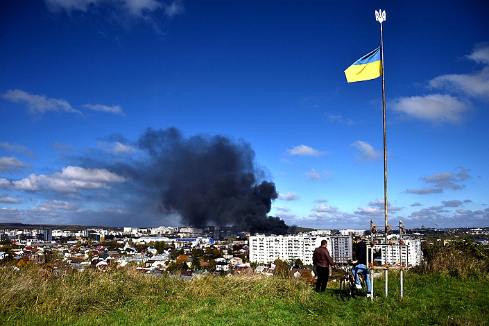 Oct. 11, 2022, A Ukrainian flag flies as local residents watch smoke rise after a Russian rocket attack on Lviv's critical infrastructure. Photo: VCG
