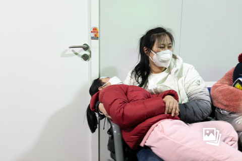 2023年3月2日，北京儿童医院发热门诊，一位发烧儿童躺在家人怀里。据北京疾控部门监测数据显示，季节性流感疫情活动强度呈现上升趋势。2月13日至2月26日，流行性感冒连续两周位居北京报告法定传染病病种首位，其中甲流占绝对优势。北京儿童医院工作人员称，发热门诊曾于25至27日迎来就诊小高峰，其中27日就诊人数超4000。图：财新 李丛汛（实习）