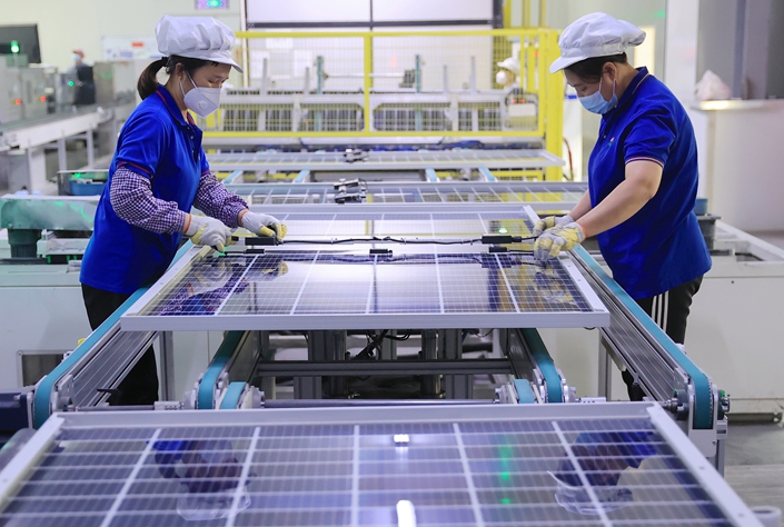 Workers produce a batch of photovoltaic cells Jan. 6, 2023, at a solar manufacturer in Dongying, Shandong province.