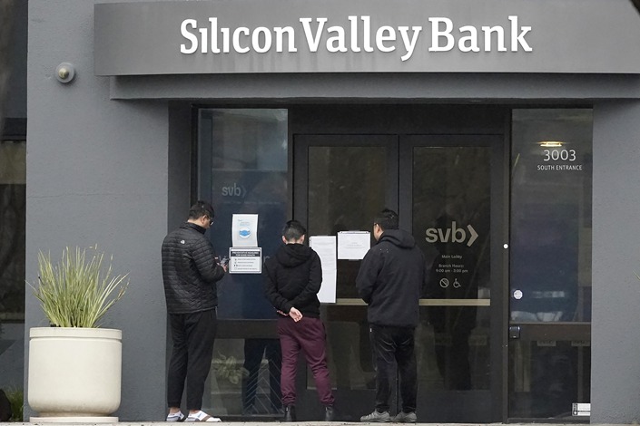 People look at signs posted outside of an entrance to Silicon Valley Bank in Santa Clara, Calif., Friday, March 10, 2023. Photo: VCG