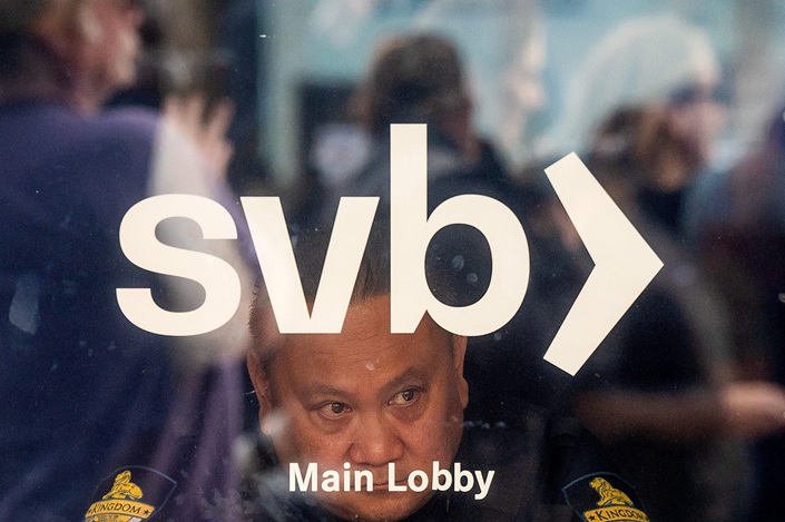 A security guard looks out a window as customers line up at Silicon Valley Bank headquarters in Santa Clara, California on March 13. Photo: VCG