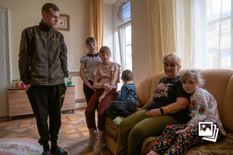 当地时间2023年5月8日，乌克兰利沃夫，17岁的Mykyta（左一），11岁的Maryna（左二），10岁的Khrystyn（左三），5岁的Bohdan（中），他们的祖母Olena（右二）和7岁的Nadia（右一）。来自斯拉夫扬斯克的Olena独自抚养她的多名孙子孙女。Olena的儿子Andriy是5个孩子的父亲，Andriy自2016年以来一直在乌克兰服役，并于2022年7月在战争中受重伤后死亡。孩子们的母亲抛弃他们后，Olena照顾起孩子们的起居。Olena和她的孩子们于2022年3月离开了条件艰苦的斯拉夫扬斯克。起初，他们都住在一所寄宿学校，后来在志愿者的帮助下，他们租了一套生活条件舒适的公寓。目前，他们居住在更加安全的乌克兰西部城市利沃夫。图：Olena Znak/视觉中国