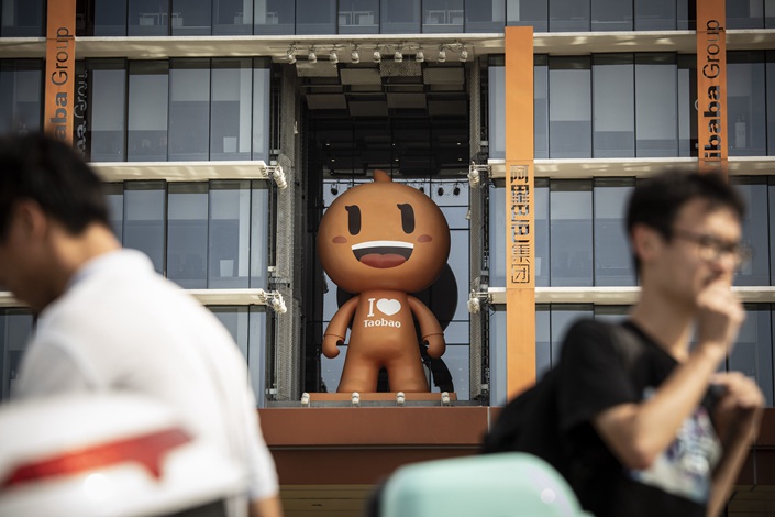 People walk past the mascot for the Taobao e-commerce platform in May 2021 at Alibaba’s headquarters in Hangzhou, East China’s Zhejiang province. Photo: Bloomberg