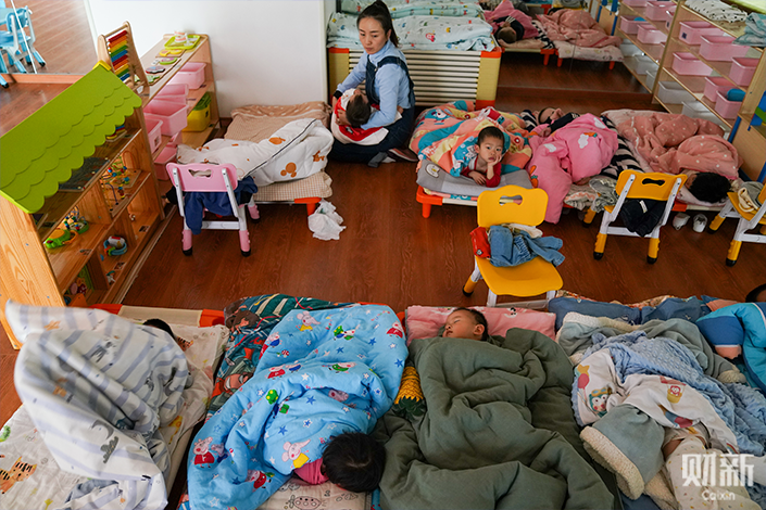 Wendy comforts a child in her arms during naptime at her in-home childcare center. Photo: Zhang Ruixue/Caixin