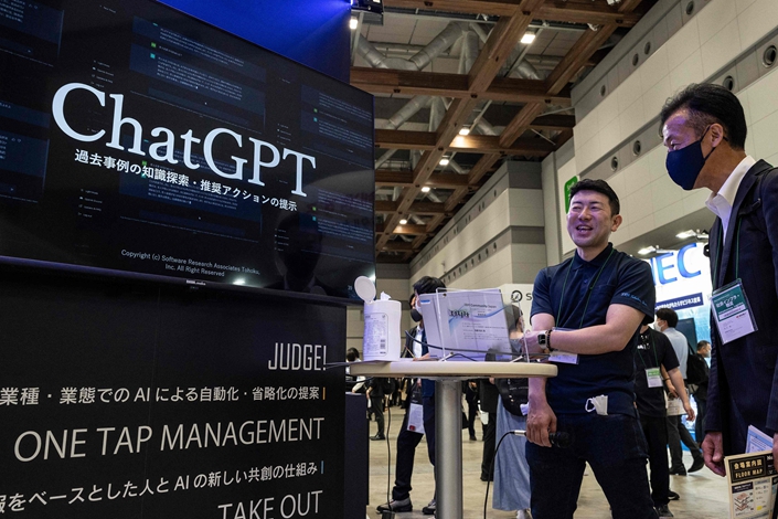 A man speaks with a booth representative (2nd R)  promoting ChatGPT at the three-day 7th AI Expo, part of NexTech Week Tokyo 2023. Photo: VCG