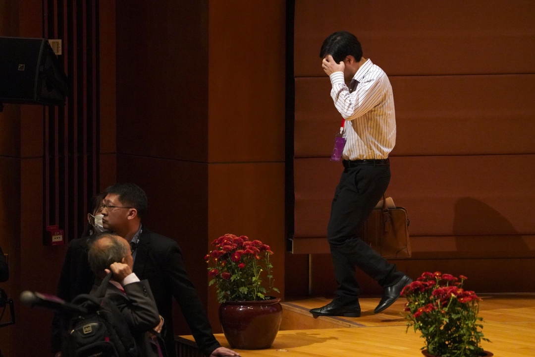 He Jiankui, who sparked near universal condemnation for creating the world’s first gene-edited babies, hides in face as he leaves the stage of a conference in Hong Kong in 2018. Photo: VCG