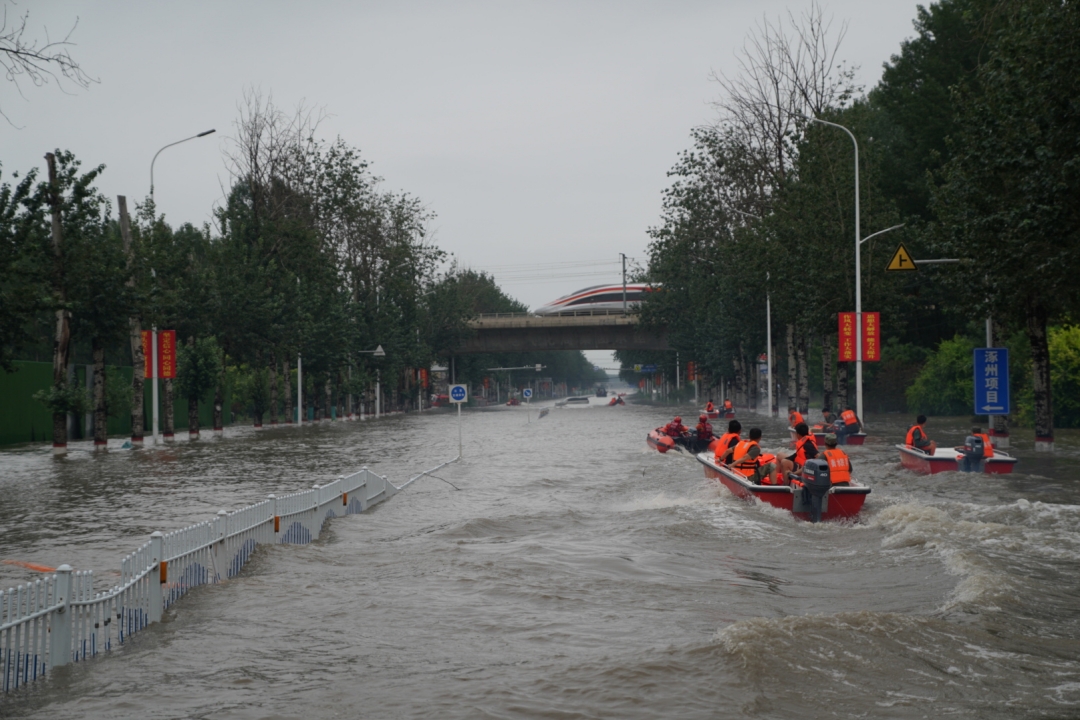 Emergency motor boats carry residents over a flooded street Tuesday in the town of Matou in Zhuozhou, North China’s Hebei province. Photo: Ding Gang/Caixin