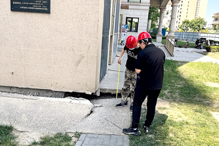 Workers assess the degree of land subsidence damage at residential buildings located in the Tianjin Country Garden community on June 7. Photo: Niu Mujiangqu/Caixin