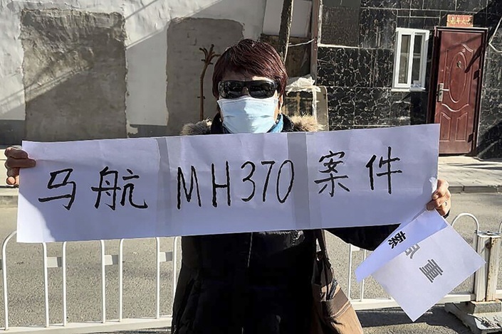 Hu Xiufang, whose son, daughter-in-law and granddaughter were aboard the missing Malaysia Airlines flight MH370, holds a banner on Monday in Beijing as a local court began hearing lawsuits against the carrier. Photo: VCG