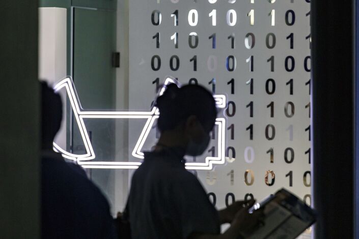 A visitor walks past a wall with binary codes at the World Artificial Intelligence Conference in Shanghai in July 2021. Photo: Bloomberg