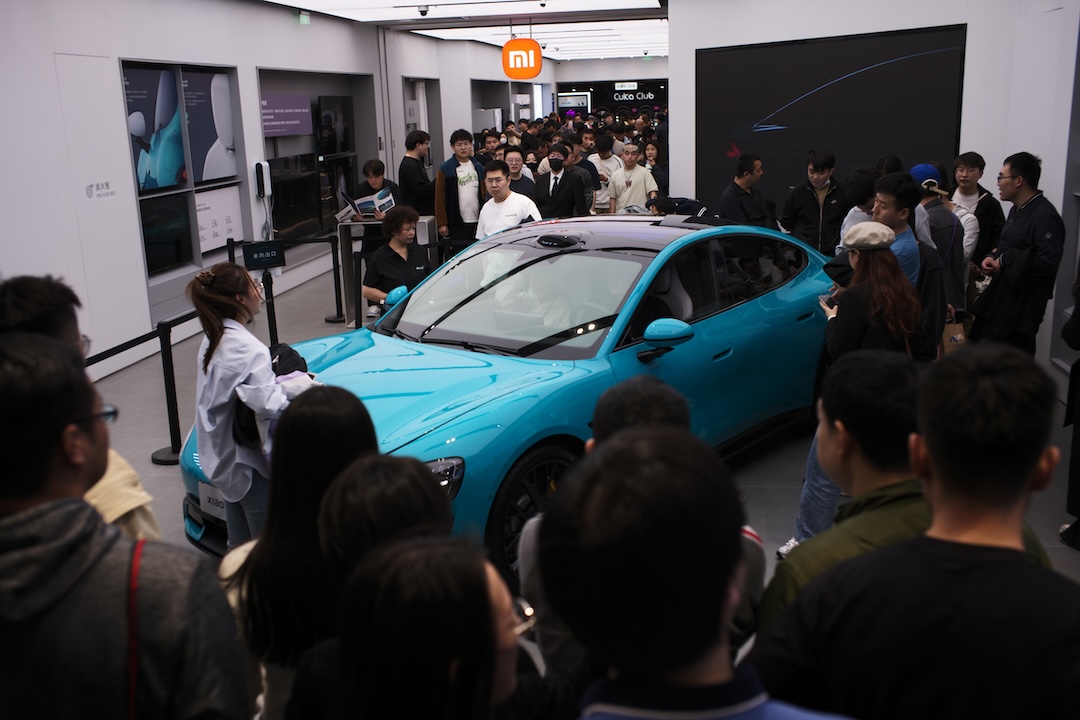 Onlookers gather around Xiaomi debut electric vehicle, the SU7, at a Xiaomi retail store in the Hesheng Hui Mall in Beijing on Saturday. Photo: Dong De/Caixin