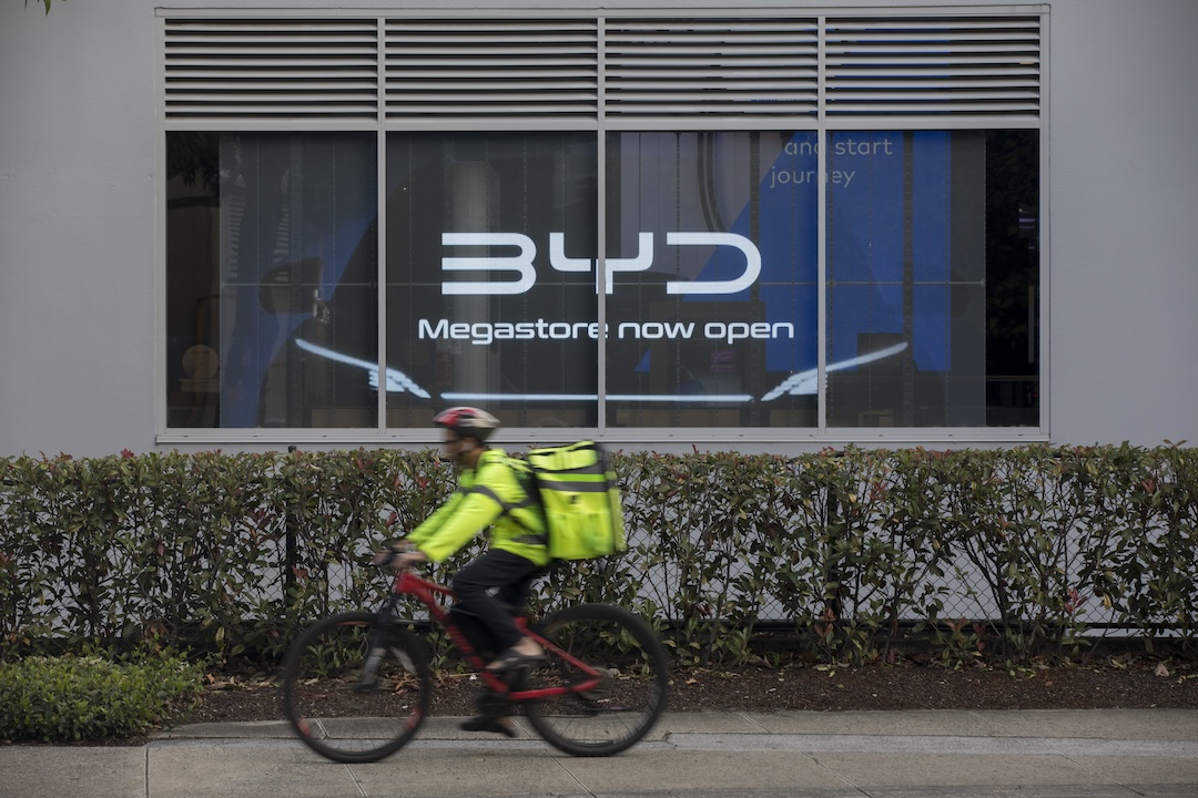 A courier rides a bicycle past a BYD experience center on March 27 in Sydney, Australia. Photo: VCG