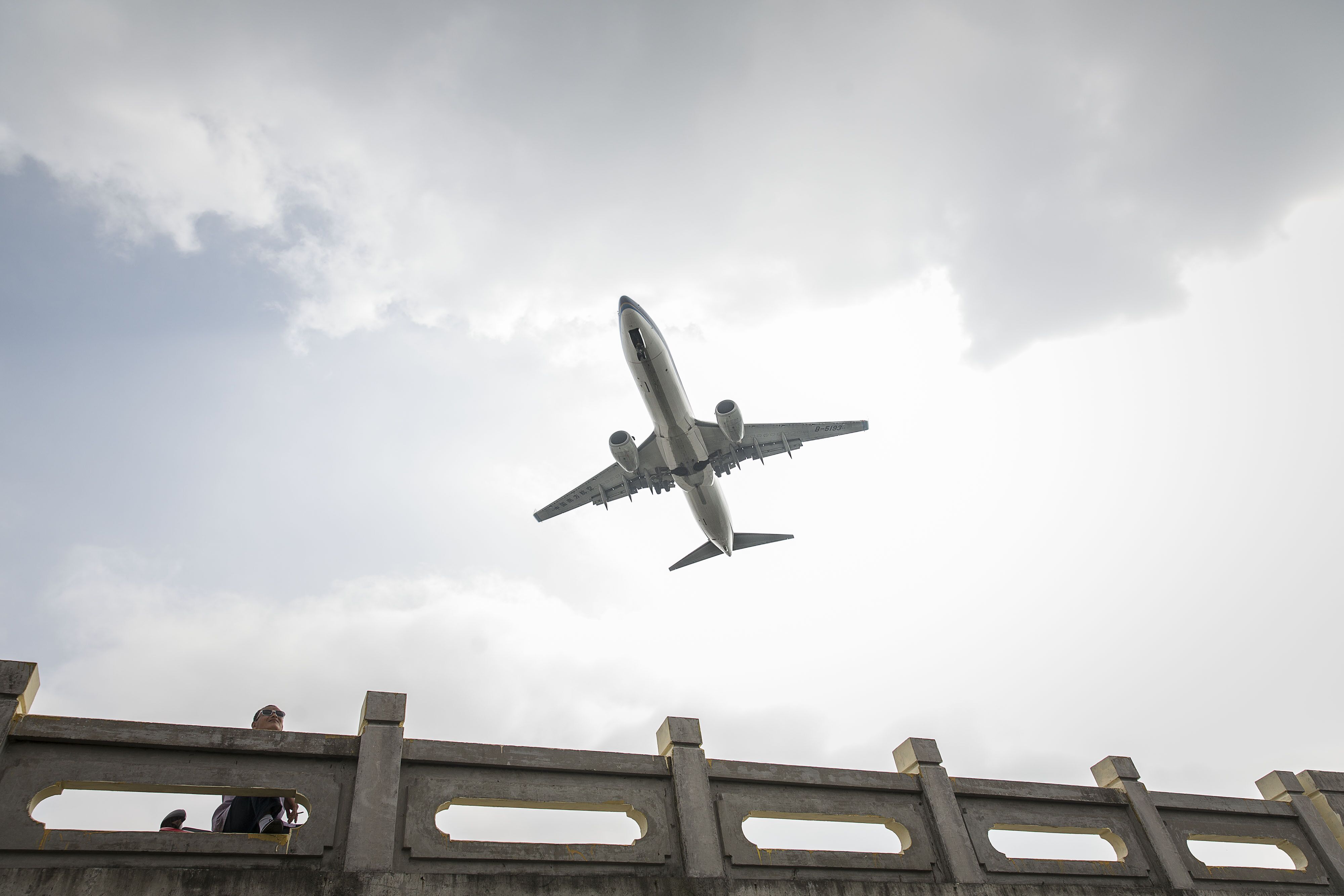 A China Southern Airlines Co. aircraft flies over a man standing on a pedestrian bridge as it approaches to land at Hongqiao Airport in Shanghai, China, on Oct. 23, 2015. Photo: Bloomberg